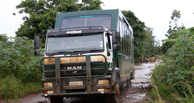 Camion de safari tout-terrain roulant sur un terrain boueux.