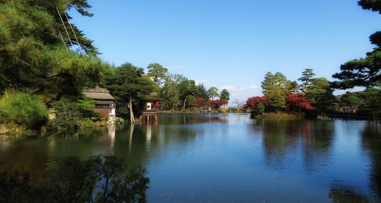 Étang tranquille entouré d'érables et de maisons de thé dans le Kenroku-en de Kanazawa en début d'automne.