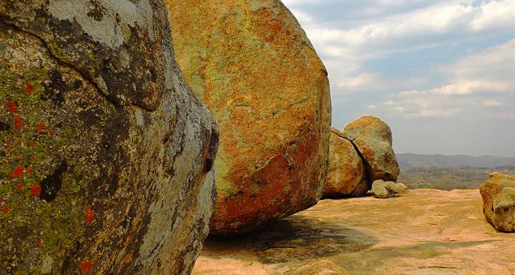 Enormes rocas de granito gastadas por el tiempo dominan una colina rocosa bajo cielos parcialmente nublados.