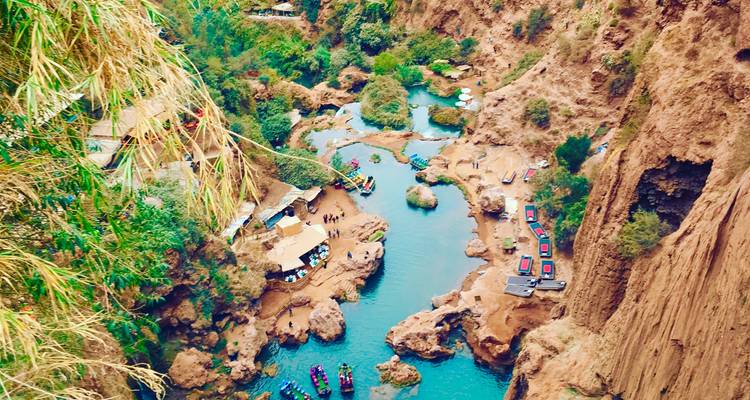 Schilderachtig uitzicht op een rotsachtige rivierbedding met kleine bootjes en groen.