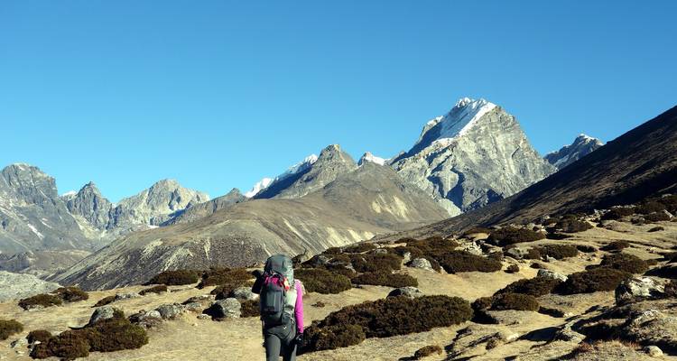 Randonneu·r·se au premier plan avec des sommets enneigés au loin.