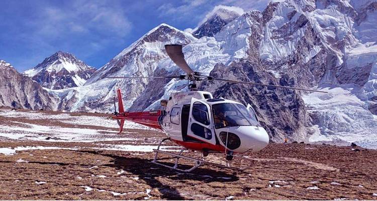 Helikopter op een besneeuwde bergketen belicht door zonlicht.