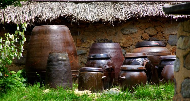 Pots en argile disposés contre une structure traditionnelle au toit de chaume.