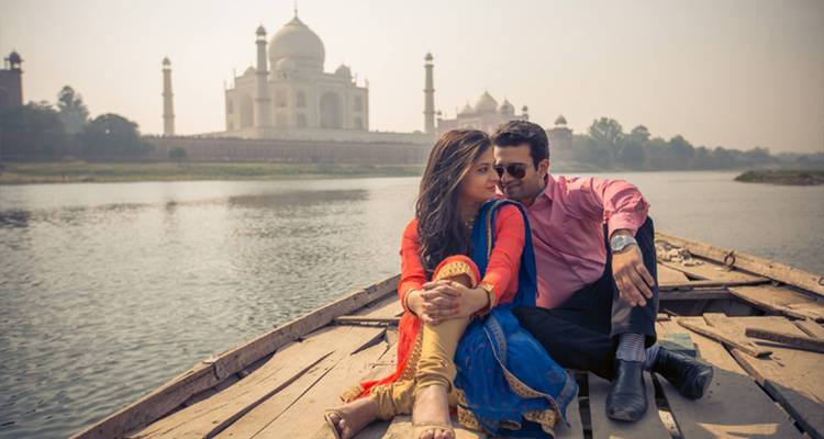 Stel zittend in een boot met de Taj Mahal op de achtergrond.