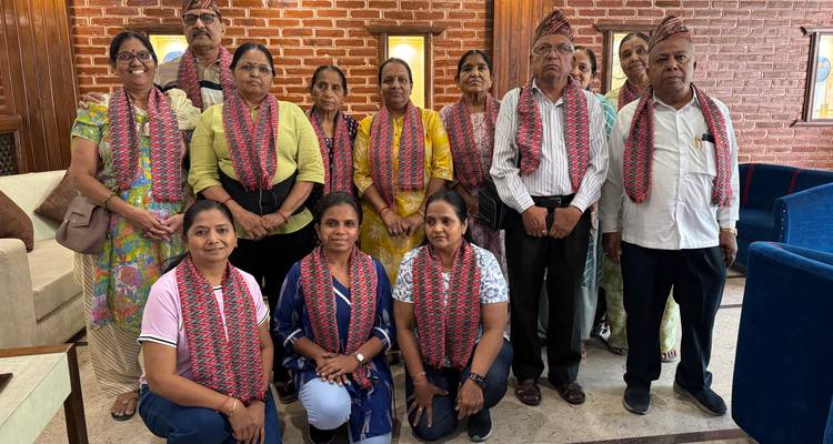 Große Gruppe von Menschen, die drinnen mit traditionellen Schals posiert.