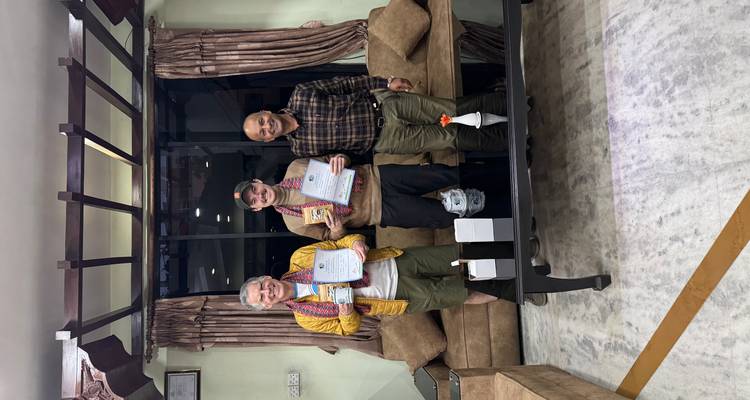 Drei Personen drinnen, die Zertifikate halten.