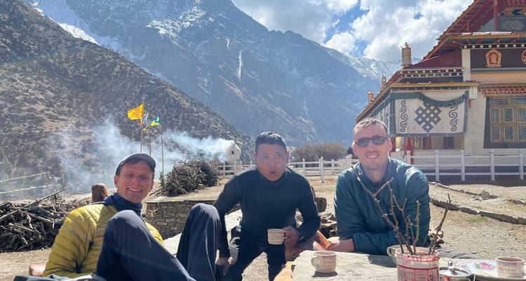 Drei Männer genießen einen malerischen Bergblick mit einem Tempel in der Nähe.