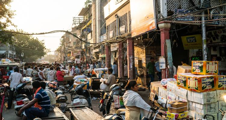 Busy street market scene with people, vehicles, and stalls in Delhi.