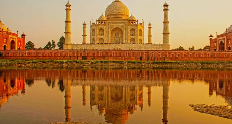 Taj Mahal reflecting in water at sunset.