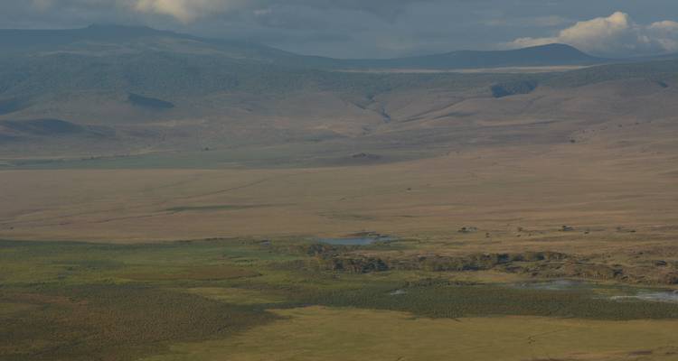 Weite Ebenen mit verstreuten Gewässern, umgeben von Bergen.