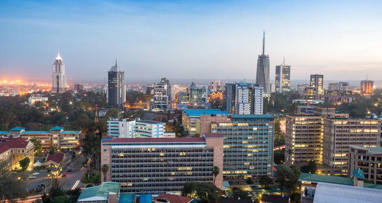 Nairobi stadsbeeld bij schemering met verlichte gebouwen en zonsonderganglucht.