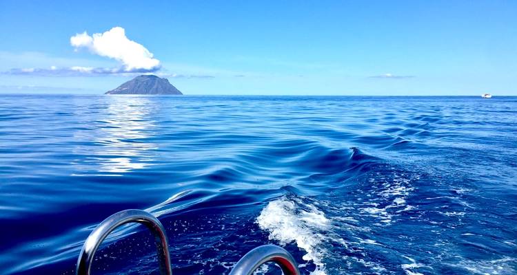 Blick von einem Boot auf eine entfernte Insel im Meer.