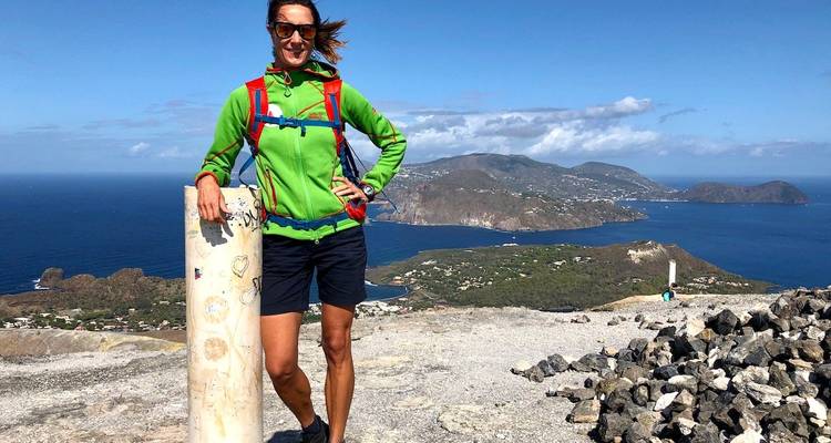 Frau posiert auf einem Berg mit Meerblick.