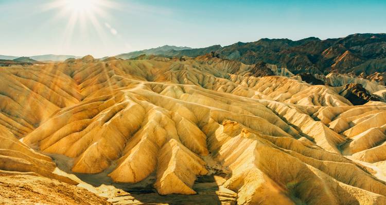 Les terres stériles dorées de Death Valley illuminées par le soleil matinal bas avec des crêtes dramatiques