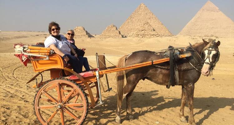 Touristen auf einer Pferdekutsche mit Pyramiden im Hintergrund