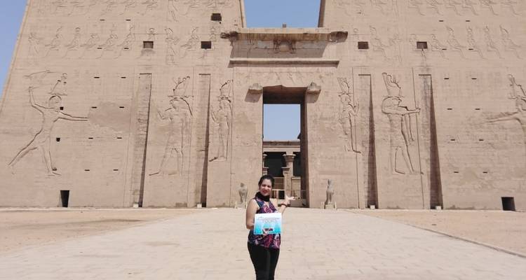 Een toerist voor de Edfu-tempel die een tourbord vasthoudt.