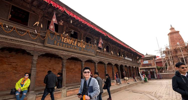 Street view in Bhaktapur with people walking and traditional buildings.