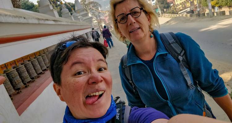 Two people taking a selfie in front of a building with prayer wheels.