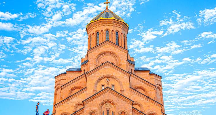 Grote kathedraal met een gouden koepel en toeristen ervoor.