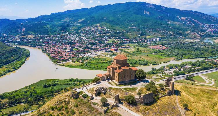 Luchtfoto van een historische kerk op een heuvel met een rivier eronder.
