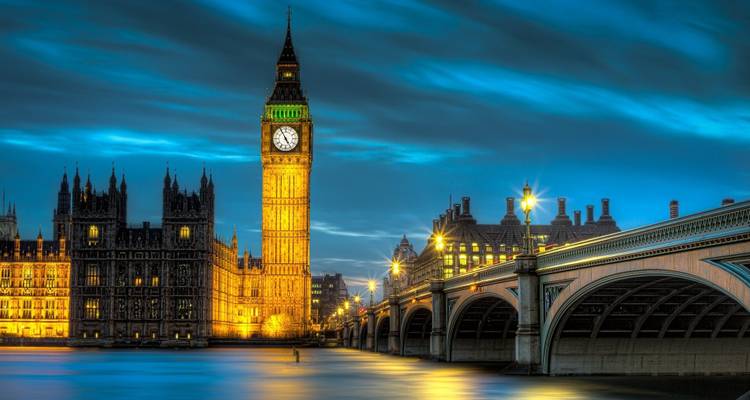 Big Ben illuminé et les Maisons du Parlement se reflétant sur la Tamise sous un ciel crépusculaire dramatique.