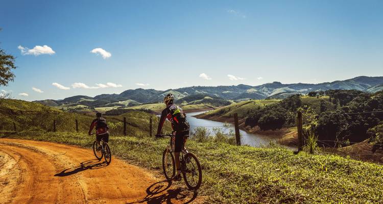 Cyclistes roulant sur un sentier de terre dans des paysages vallonnés.