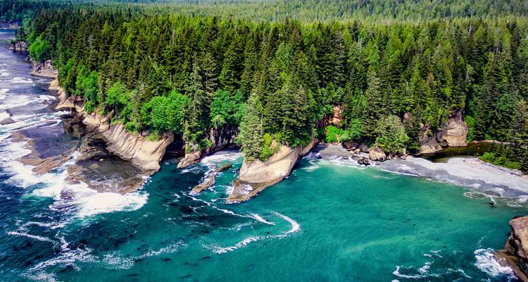 Luchtfoto van de kust met türkooise baaitjes en rotsachtige, beboste voorgebergten op Vancouver Island.