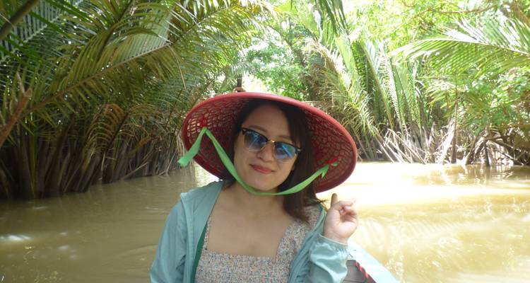 Mujer sonriendo en un barco rodeada de vegetación exuberante y vías fluviales.