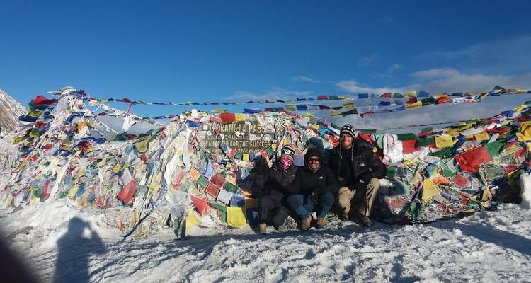 Gruppe von Menschen am Thorong La Pass mit bunten Fahnen im Schnee.
