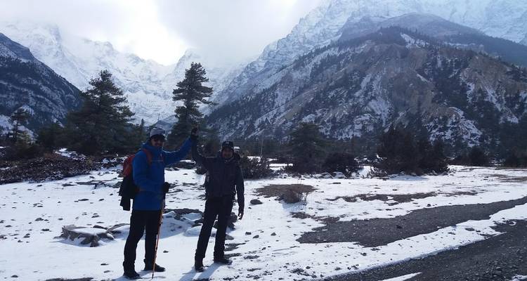 Zwei Wanderer mit erhobenen Armen in verschneiter Berglandschaft.