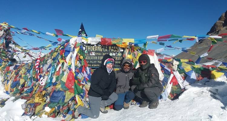 Gruppe posiert am Thorong La Pass mit Schnee und Flaggen.