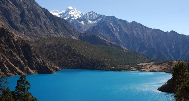Een levendig blauw meer omringd door hoge, met sneeuw bedekte bergen.