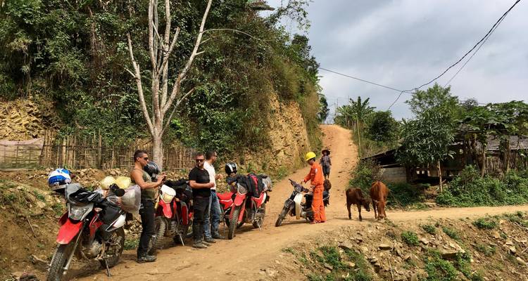 Eine Gruppe von Motorradfahrern, die auf einem Feldweg in ländlicher Umgebung rastet.