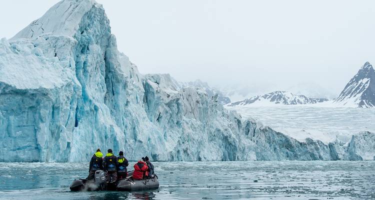 Groupe dans un bateau près d'un grand glacier.