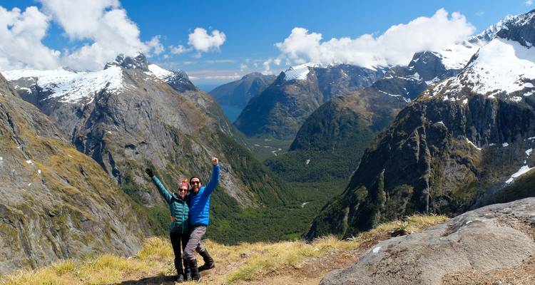 Glückliche Wanderer feiern auf einem Bergrücken mit dramatischen schneebedeckten Fiordland-Gipfeln im Hintergrund