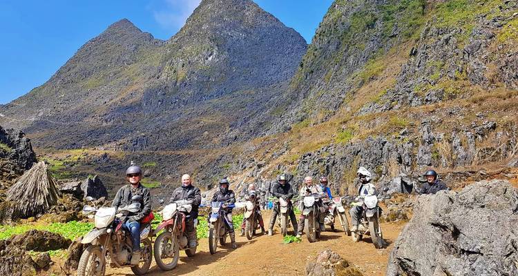 Gruppe von Motorradfahrern, die vor felsigen Hügeln posieren.
