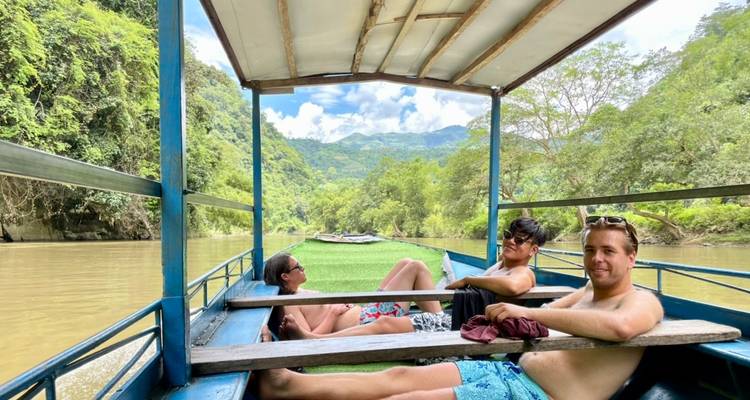 Menschen entspannen bei einer Bootsfahrt entlang eines Flusses mit viel Grün.