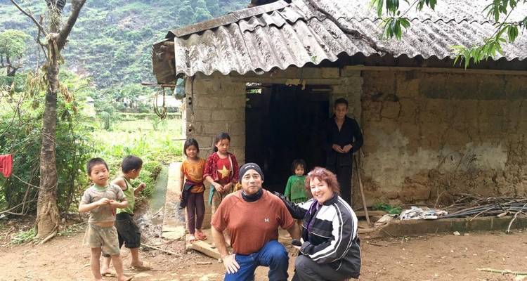 Volwassenen en kinderen rond een rustiek huis in een landelijke omgeving.