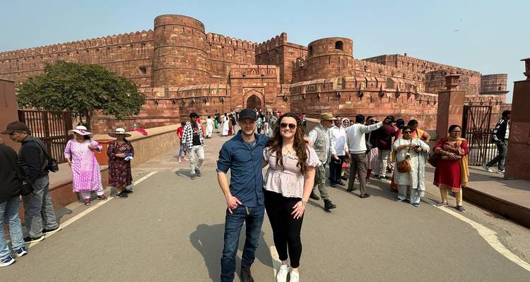 Paar, die auf der Hauptstraße posiert, mit den roten Sandsteinbastionen des Agra Fort und einer Menschenmenge im Hintergrund