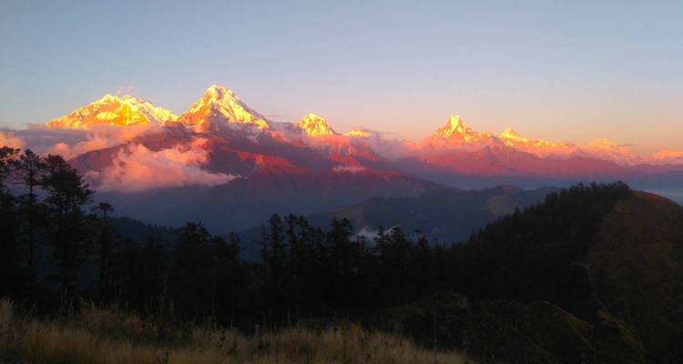 Schneebedeckte Berge bei Sonnenuntergang mit orangenem Glühen.