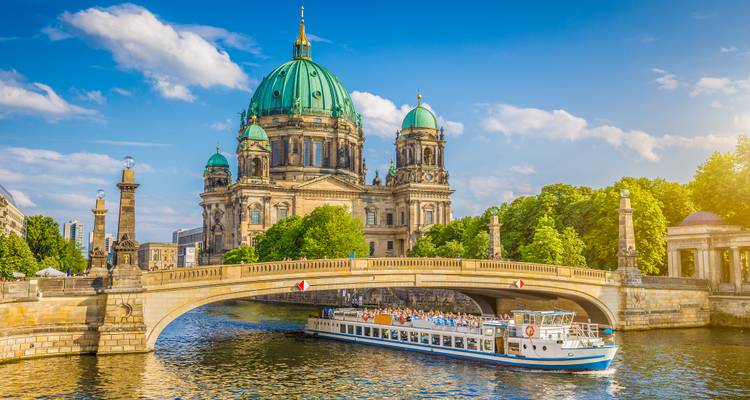 Berliner Dom mit einem vorbeifahrenden Flusskreuzfahrtschiff.