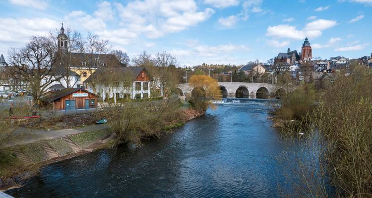Riverside view of a town with an old stone bridge.