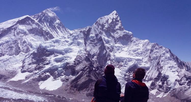 Two people gazing at snow-covered mountain peaks.