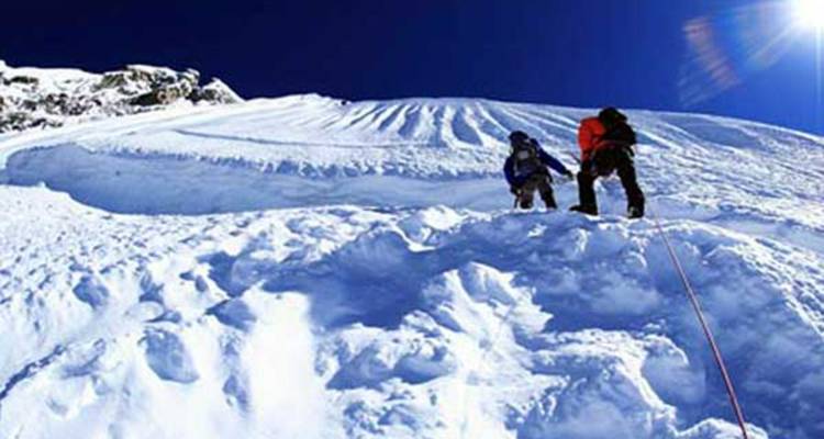 Twee klimmers die een steile sneeuwbelling beklimmen.