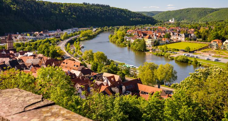 Scenic view of a river and town surrounded by green hills.