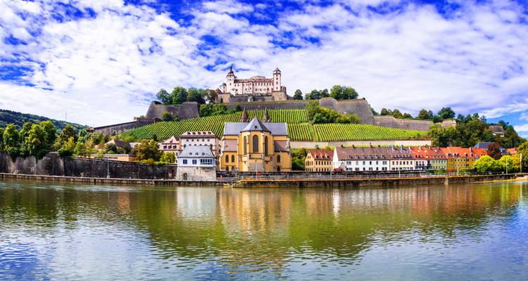 Fortress on a hill overlooking a river with vineyards.