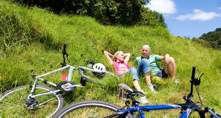 Couple se détendant avec des vélos dans une zone herbeuse.