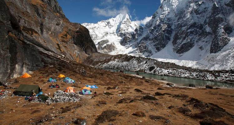 Hooggelegen bergkamp met tenten en majestueuze besneeuwde toppen.