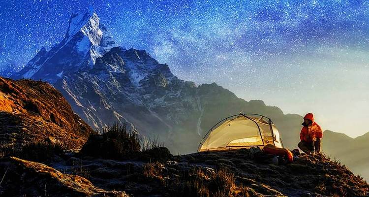 Camper unter einem Sternenhimmel mit Bergkulisse.
