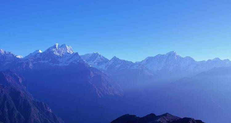 Mountain range with snow under a clear blue sky.